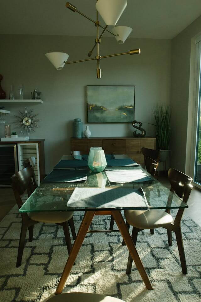 Modern dining room with a glass table, mid-century style chairs, and a brass chandelier.