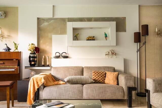 A cozy living room with a gray sofa, a glass coffee table, and a piano in the background.