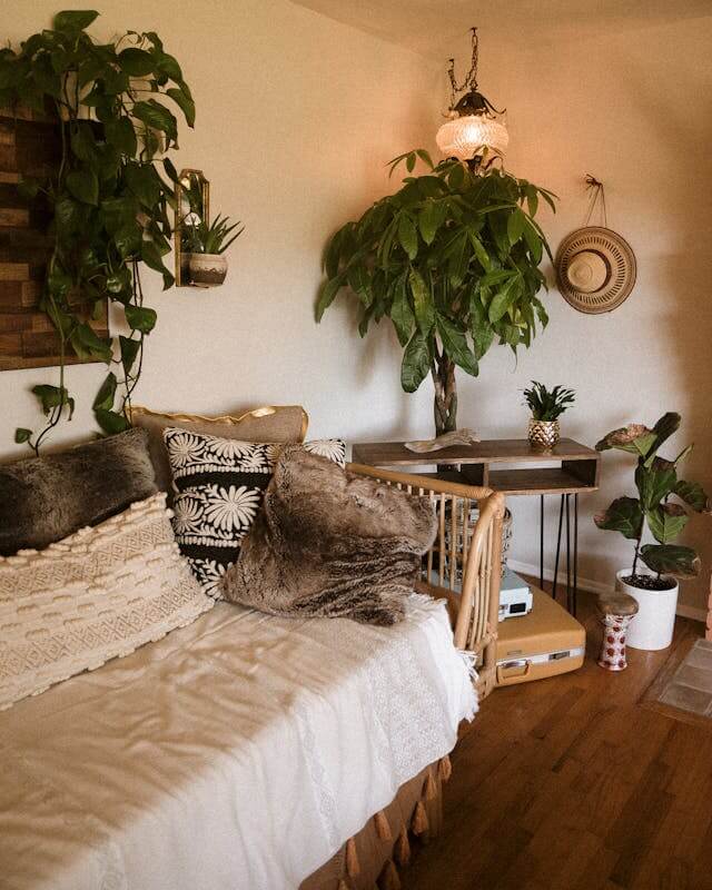 Cozy bedroom corner with plants and textured pillows on the bed.