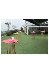 A Hexagon Bar Table™ with red and yellow chairs on a green grass.