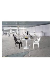 A white table and Replica Louis Ghost Chairs in a large room.