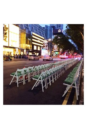 a row of classic white folding chairs on a city street