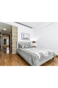 a bedroom with wooden floors and a napier queen bed light grey