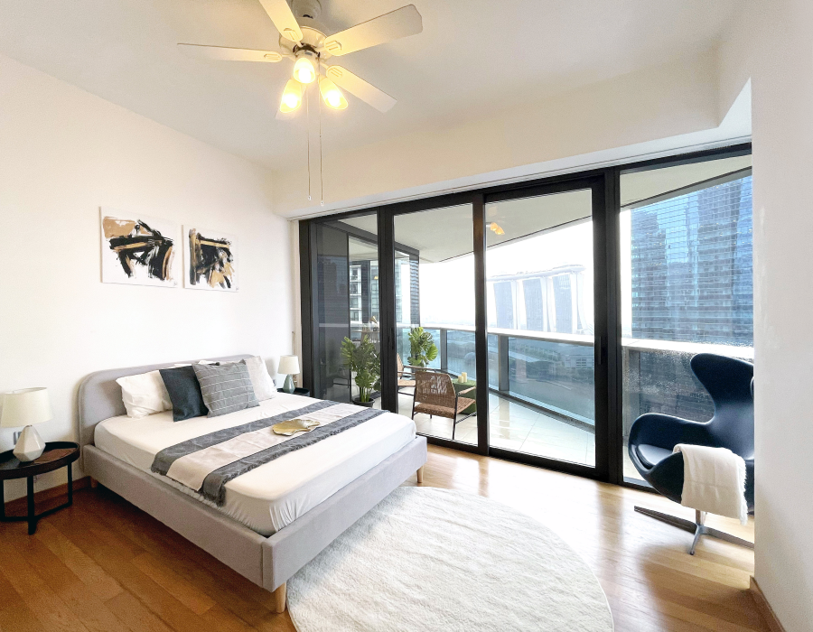 A bedroom with a bed and a balcony overlooking the city.