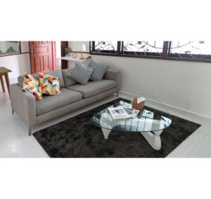 A Home Staging - Housing Development Board (HDB) flat features a modern living room with a gray sofa, patterned cushions, glass coffee table with books, and dark rug on a white tile floor.