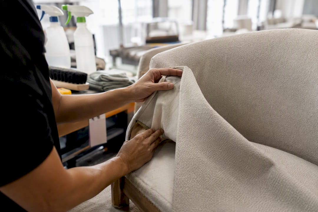 Hands cleaning upholstered chair in refurbishment workshop
